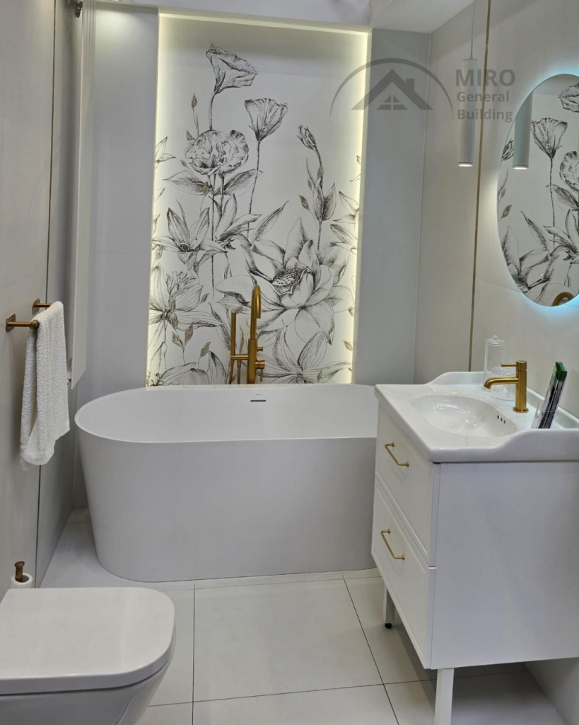 uxury bathroom renovation London with freestanding bathtub, marble wall panels and gold fittings.
